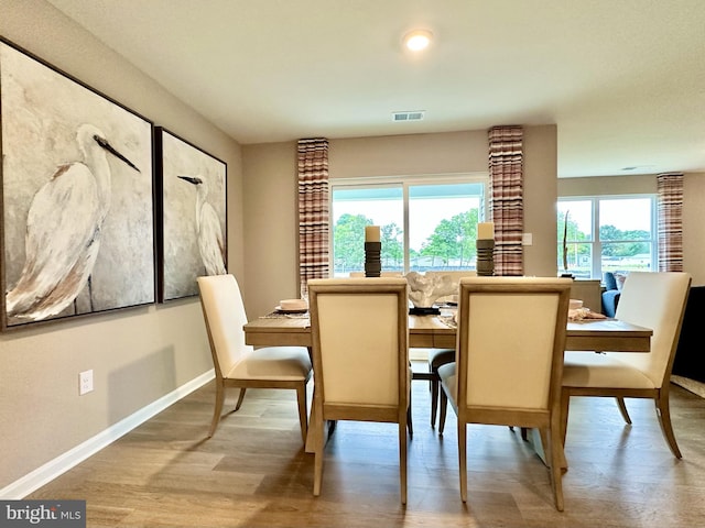 dining space featuring light wood-type flooring, visible vents, and baseboards