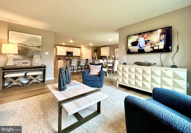 living area with light wood-style flooring, baseboards, and recessed lighting