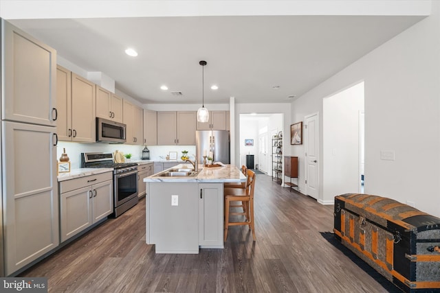 kitchen featuring recessed lighting, a sink, appliances with stainless steel finishes, dark wood-style floors, and a center island with sink