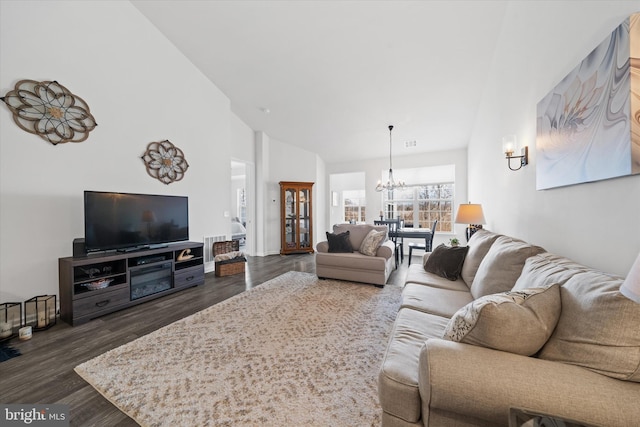 living area featuring dark wood-style floors, visible vents, a notable chandelier, and high vaulted ceiling