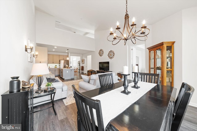 dining space featuring high vaulted ceiling, dark wood-type flooring, and a notable chandelier