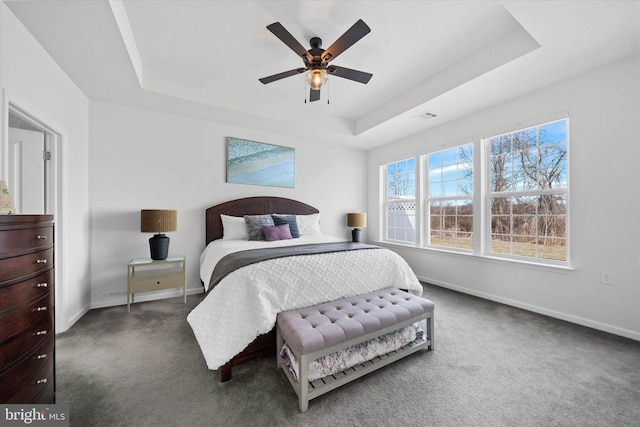 bedroom with carpet floors, a tray ceiling, visible vents, a ceiling fan, and baseboards