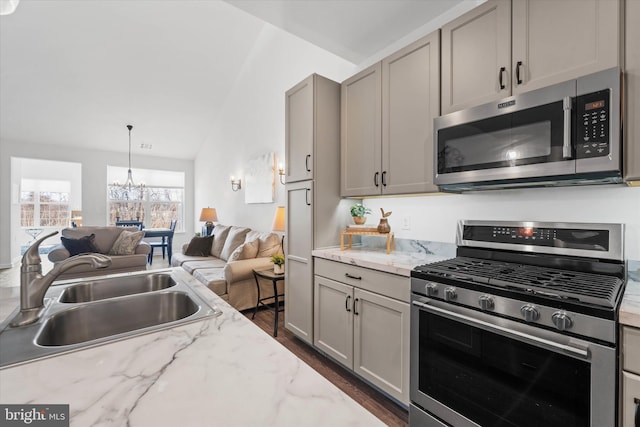 kitchen with dark wood-style flooring, appliances with stainless steel finishes, open floor plan, a sink, and a chandelier