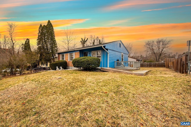 view of front of property featuring fence, a deck, board and batten siding, and a front yard