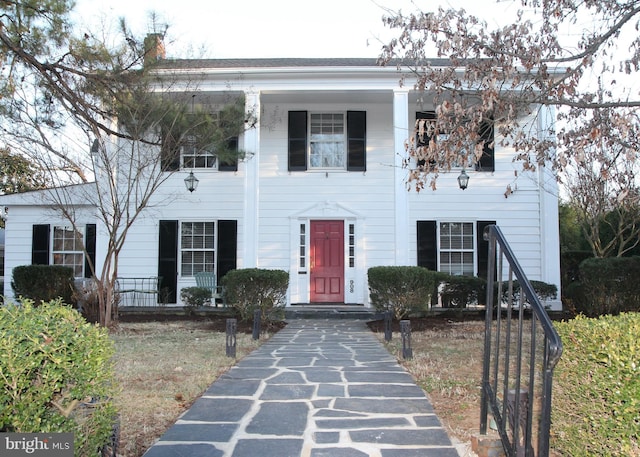 greek revival house with a porch and a chimney