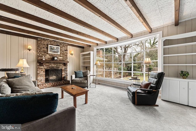 carpeted living area with a brick fireplace and beamed ceiling