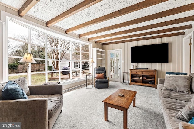 living area with beam ceiling, carpet, and wooden walls