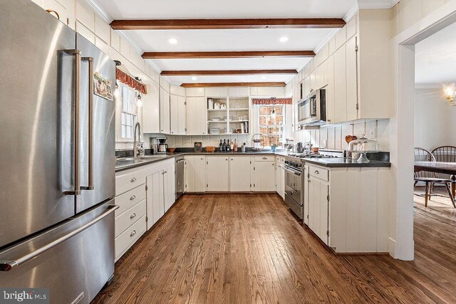 kitchen featuring dark countertops, dark wood-style floors, premium appliances, and beam ceiling