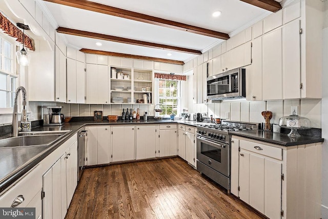 kitchen with dark countertops, beamed ceiling, dark wood-style floors, stainless steel appliances, and a sink