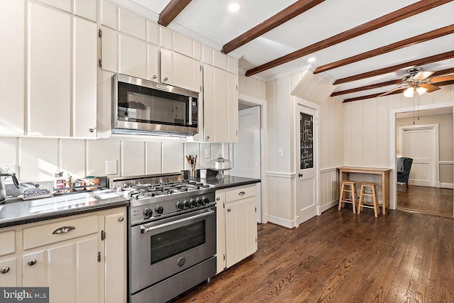 kitchen featuring beamed ceiling, dark countertops, dark wood finished floors, stainless steel appliances, and white cabinets