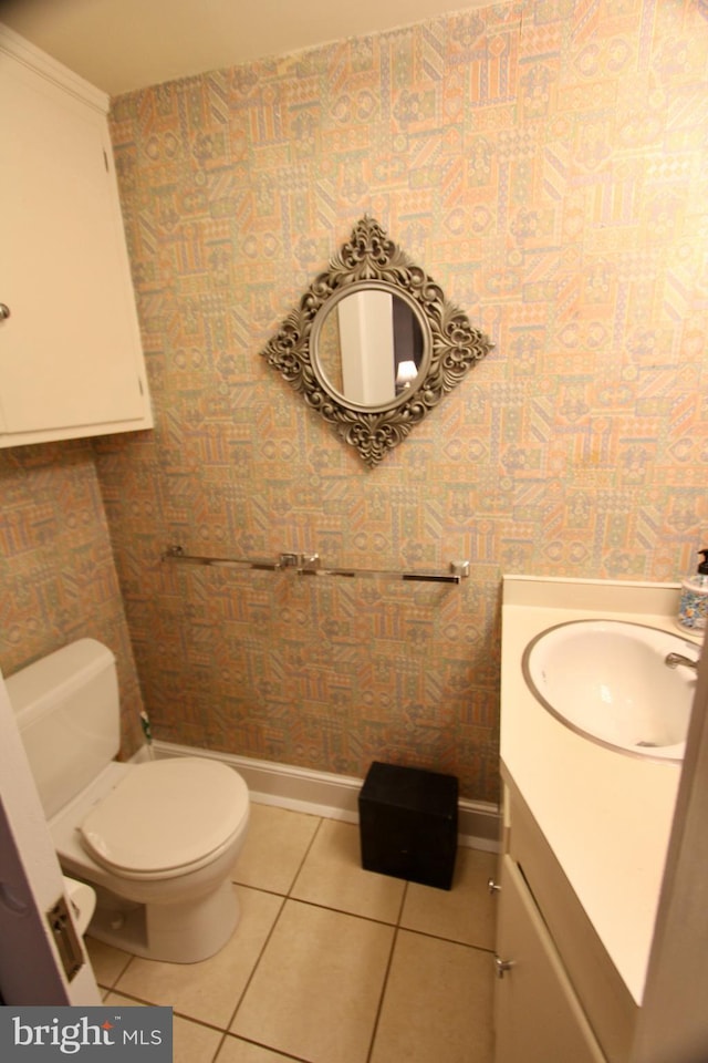 bathroom featuring wallpapered walls, baseboards, toilet, tile patterned floors, and vanity