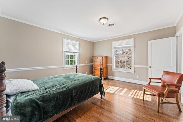 bedroom featuring visible vents, ornamental molding, baseboards, and wood finished floors