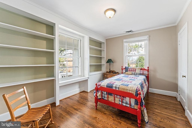 bedroom featuring visible vents, baseboards, wood finished floors, and crown molding