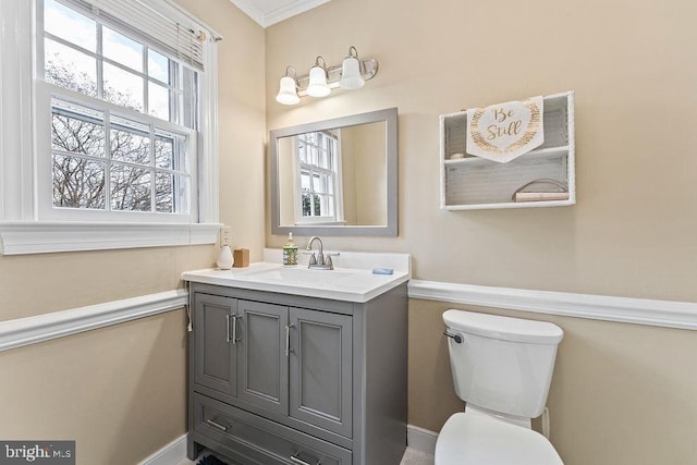 half bath featuring toilet, ornamental molding, and vanity