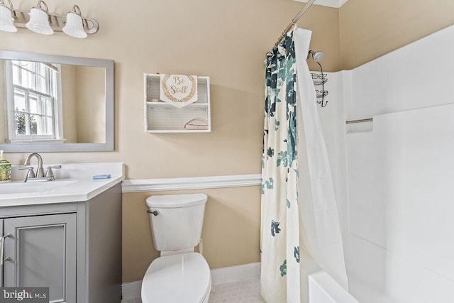 full bath with toilet, vanity, baseboards, and shower / bath combo