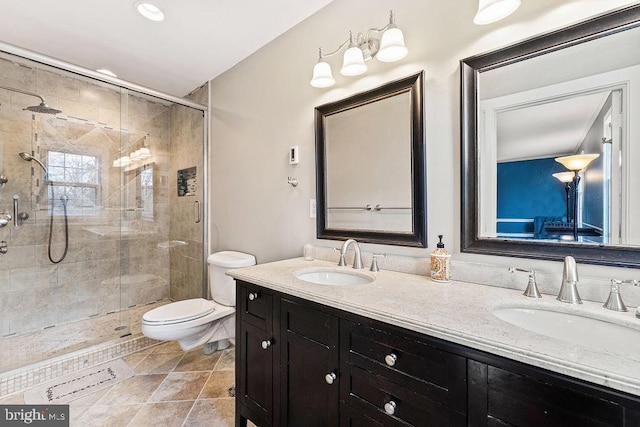 full bathroom featuring double vanity, a shower stall, toilet, and a sink