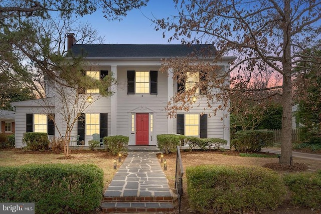 neoclassical / greek revival house featuring a chimney