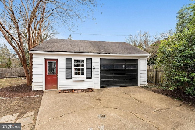 view of front of home with an outdoor structure, concrete driveway, fence, and a garage