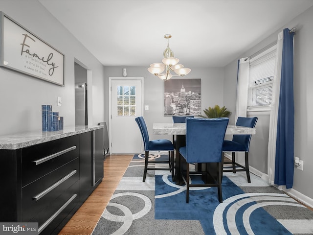 dining area featuring light wood-style flooring, baseboards, and an inviting chandelier