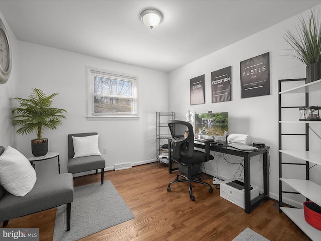 office area with wood finished floors, visible vents, and baseboards