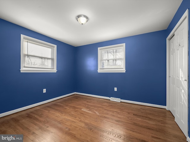 unfurnished bedroom with a closet, visible vents, multiple windows, and baseboards