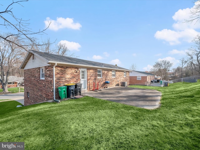 back of house with central AC, a patio area, brick siding, and driveway