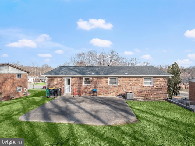 rear view of house with a patio, central air condition unit, a yard, and brick siding