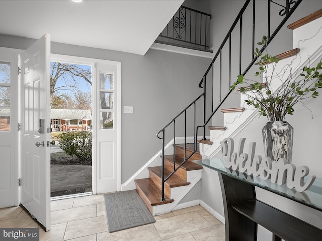 entrance foyer with light tile patterned floors, stairway, and baseboards