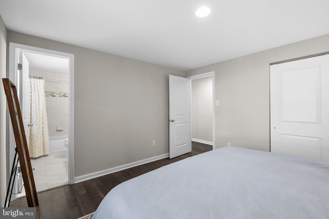 bedroom featuring ensuite bath, dark wood-type flooring, and baseboards