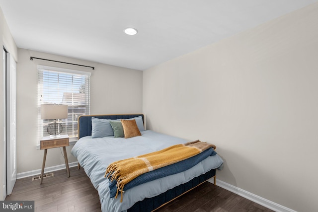 bedroom with visible vents, baseboards, and wood finished floors