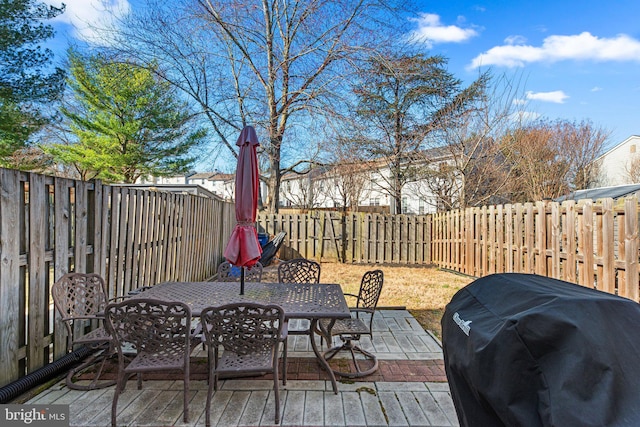 deck with outdoor dining space, a grill, and a fenced backyard