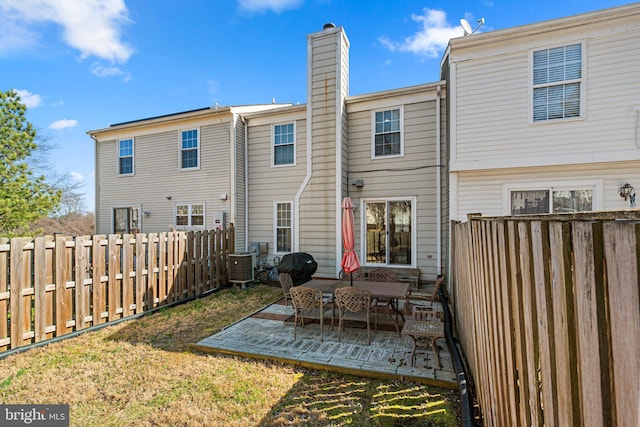 back of property featuring a fenced backyard, cooling unit, a yard, a chimney, and a patio area