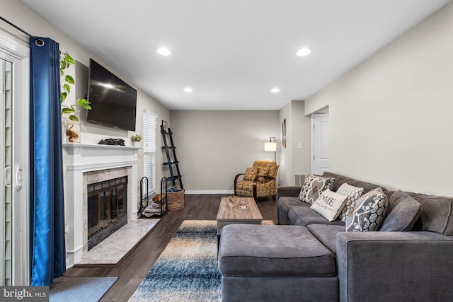 living room with visible vents, baseboards, dark wood finished floors, a premium fireplace, and recessed lighting