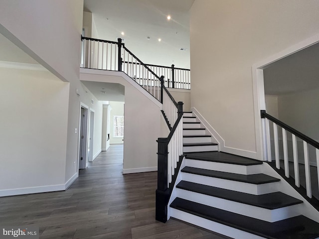 stairs with visible vents, baseboards, wood finished floors, a high ceiling, and recessed lighting