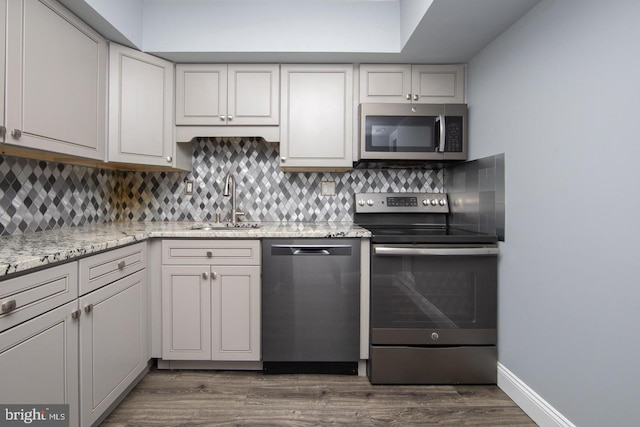 kitchen featuring dark wood-type flooring, decorative backsplash, stainless steel appliances, and a sink