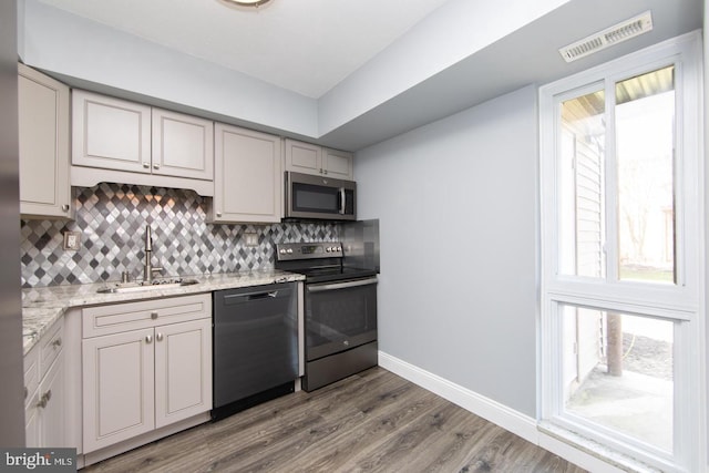 kitchen with stainless steel appliances, a sink, visible vents, and decorative backsplash
