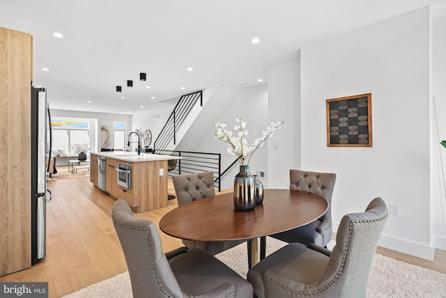 dining room with stairs, recessed lighting, light wood-type flooring, and baseboards