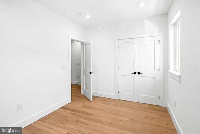 unfurnished bedroom featuring a closet, recessed lighting, light wood-style flooring, and baseboards