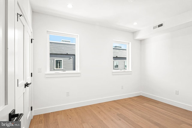 unfurnished bedroom featuring multiple windows, baseboards, visible vents, and light wood finished floors