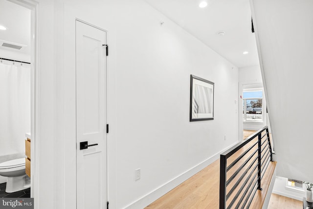 hall with recessed lighting, visible vents, light wood-style flooring, and baseboards