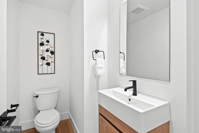 bathroom featuring visible vents, toilet, wood finished floors, baseboards, and vanity