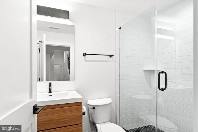 bathroom featuring visible vents, a stall shower, toilet, and vanity