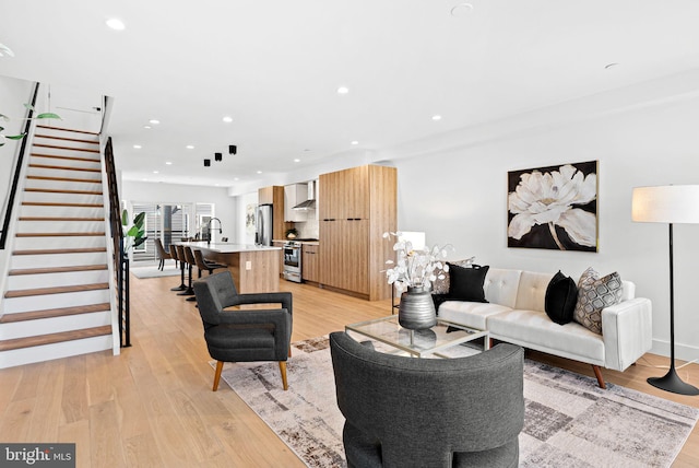 living area with recessed lighting, light wood-style flooring, and stairs