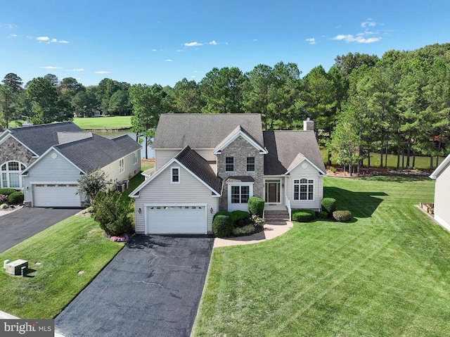 traditional-style house with aphalt driveway, a chimney, a front yard, a garage, and stone siding