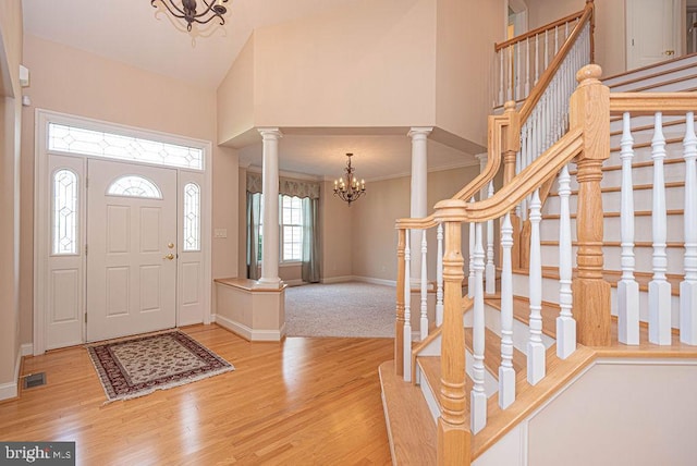 entrance foyer with ornate columns, high vaulted ceiling, a notable chandelier, and wood finished floors