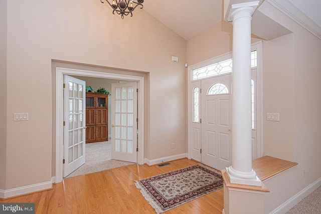 foyer entrance with visible vents, light wood-style flooring, decorative columns, and baseboards