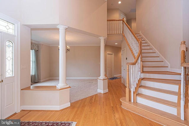 foyer entrance featuring ornate columns, stairs, a high ceiling, and wood finished floors