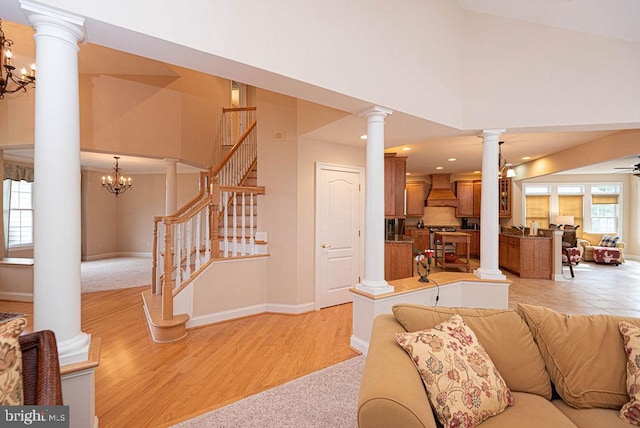 living room featuring light wood-type flooring, ornate columns, stairs, and baseboards