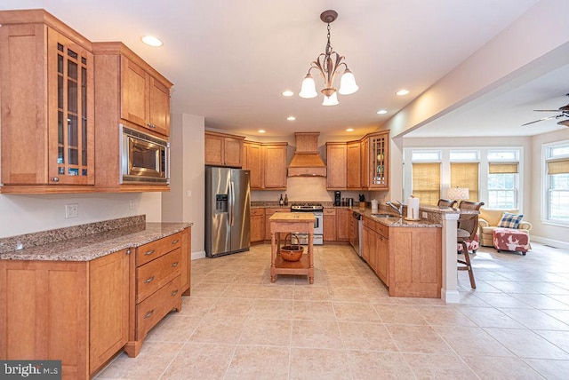 kitchen with stainless steel appliances, brown cabinetry, a peninsula, and custom exhaust hood