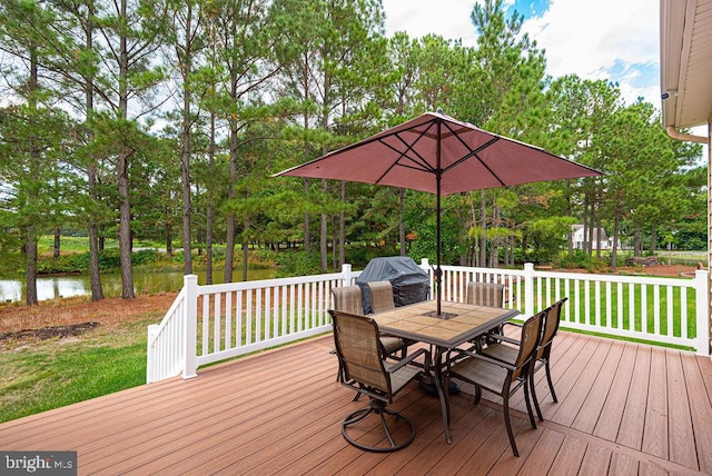 wooden terrace featuring outdoor dining space, a water view, a lawn, and grilling area